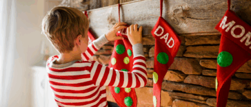 child hanging Christmas stocking on fireplace mantle