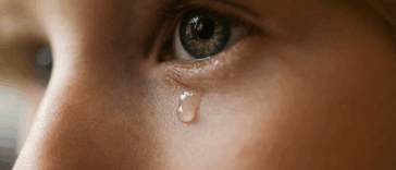 A child with a single tear falling dow their face.