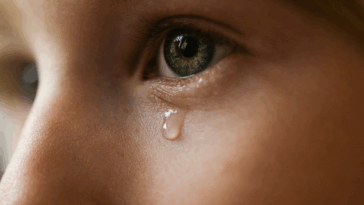 A child with a single tear falling dow their face.