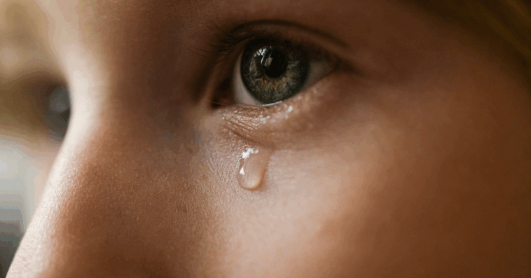 A child with a single tear falling dow their face.