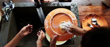 A direct above shot of a mother and daughter washing dishes near sink in kitchen, during vacation.