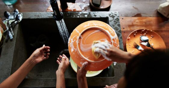A direct above shot of a mother and daughter washing dishes near sink in kitchen, during vacation.