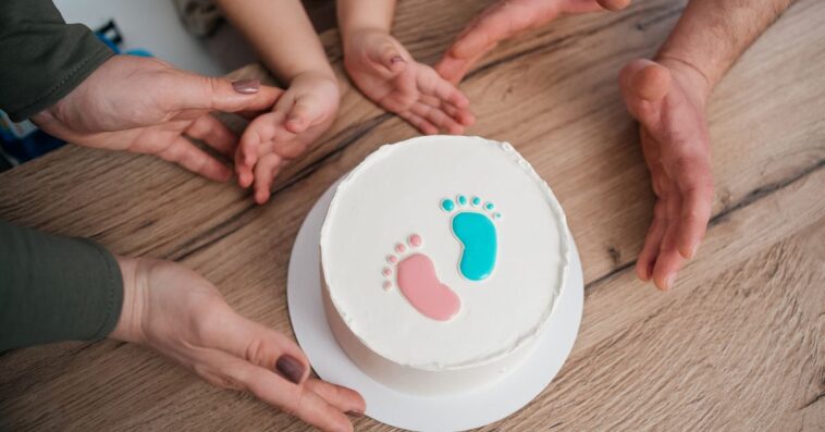 Family looking at a gender reveal cake, celebrating the upcoming birth of a baby.