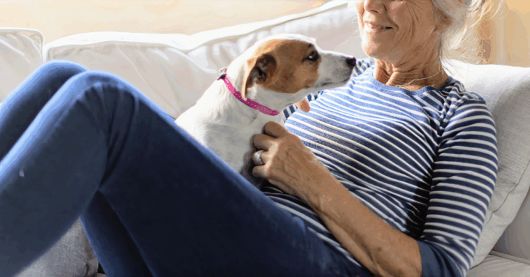 older woman laying on couch with small dog in her lap