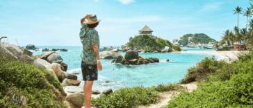 A man standing alone on a beach looking out at the ocean.