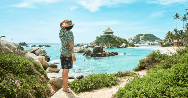 A man standing alone on a beach looking out at the ocean.