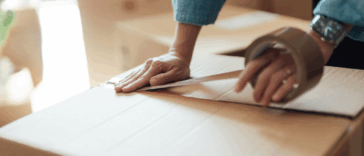 A woman putting tape on a moving box.