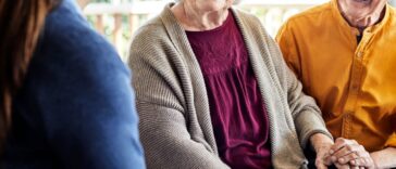 Caregiver with happy senior couple. Smiling elderly male and female are with nurse at home. They are on a home balcony home.