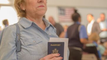 Mature woman holds a passport and boarding pass at airport.