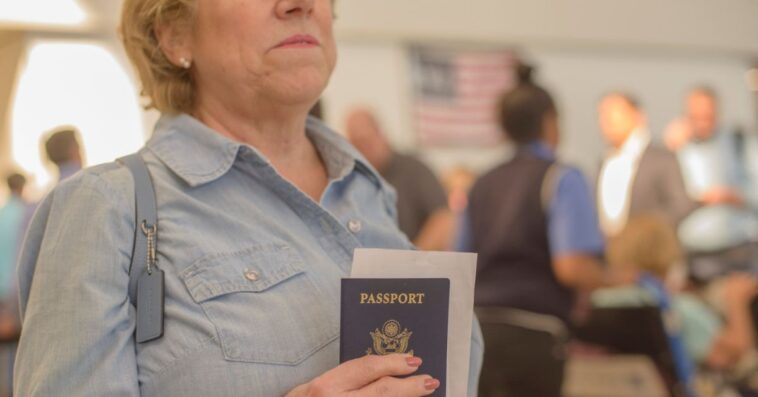 Mature woman holds a passport and boarding pass at airport.