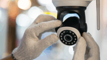 A pair of hands wearing white gloves adjusting a security camera.