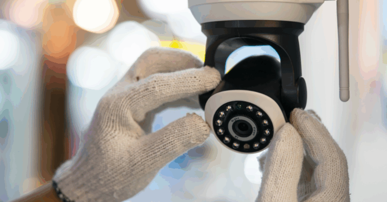 A pair of hands wearing white gloves adjusting a security camera.