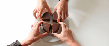 Four hands reaching for four pieces of choclolate.