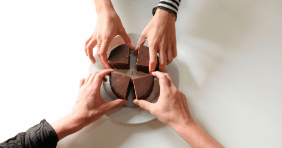 Four hands reaching for four pieces of choclolate.