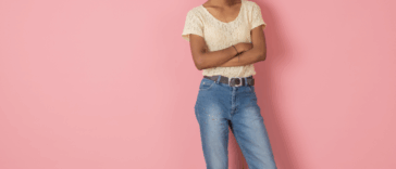 A woman folding her arms in front of a pink background