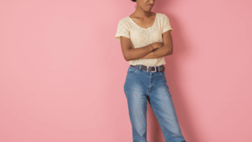 A woman folding her arms in front of a pink background
