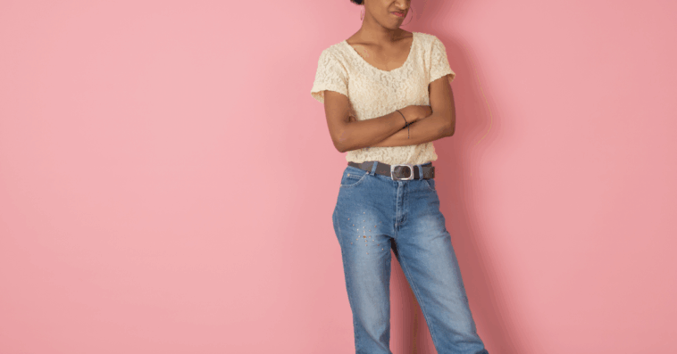 A woman folding her arms in front of a pink background