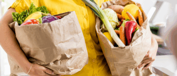 A woman holding two bags full of groceries.
