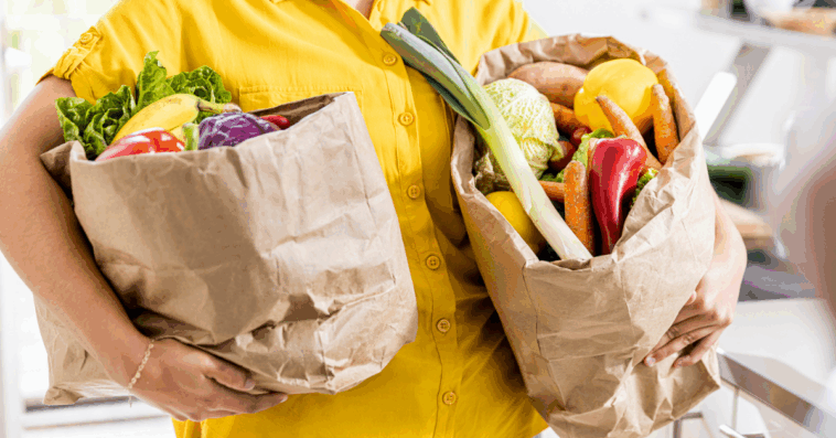 A woman holding two bags full of groceries.