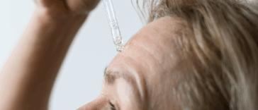 A woman applying serum to her forehead.