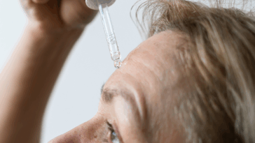 A woman applying serum to her forehead.