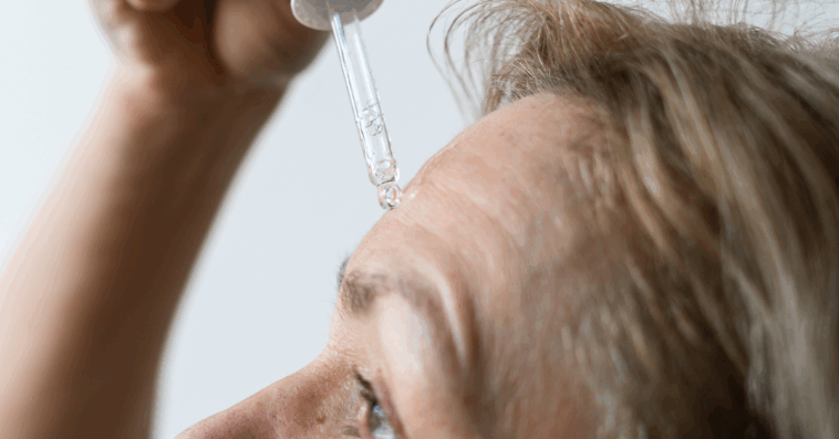 A woman applying serum to her forehead.