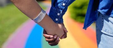 couple holding hands on rainbow walkway