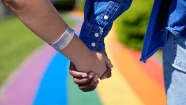 couple holding hands on rainbow walkway
