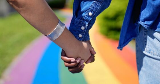 couple holding hands on rainbow walkway