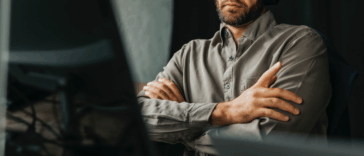 A man leaning back in an office chair folding his arms.