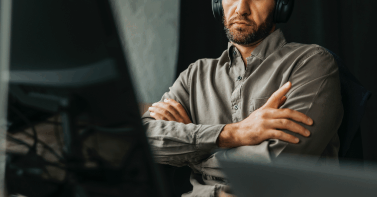 A man leaning back in an office chair folding his arms.