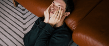 man laying on floor with hands over eyes