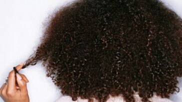 Young woman twisting hair around finger, rear view.