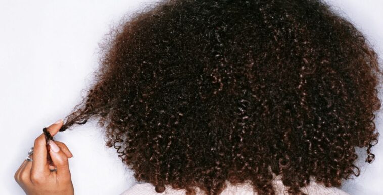 Young woman twisting hair around finger, rear view.