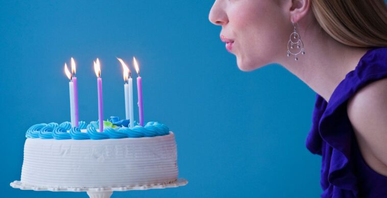Young woman blowing candles on birthday cake.