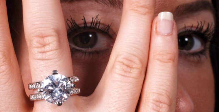 Extreme close-up shot of a beautiful young woman's eye as she shows off her diamond engagement ring - stock photo.