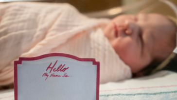 Newborn baby with name placard