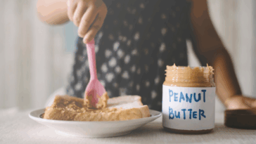 Person adding peanut butter to bread