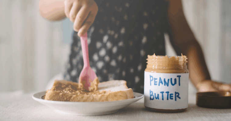 Person adding peanut butter to bread