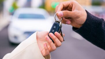 A pair of hands give a set of keys to another pair of hands.