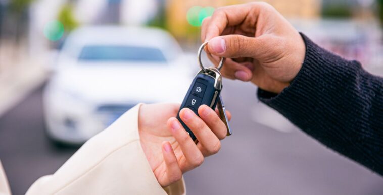 A pair of hands give a set of keys to another pair of hands.