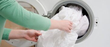 Woman taking sheet from washing machine.