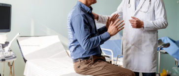 A. man sitting on an examination table talking to a doctor.