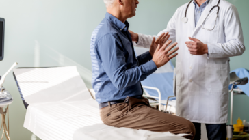 A. man sitting on an examination table talking to a doctor.
