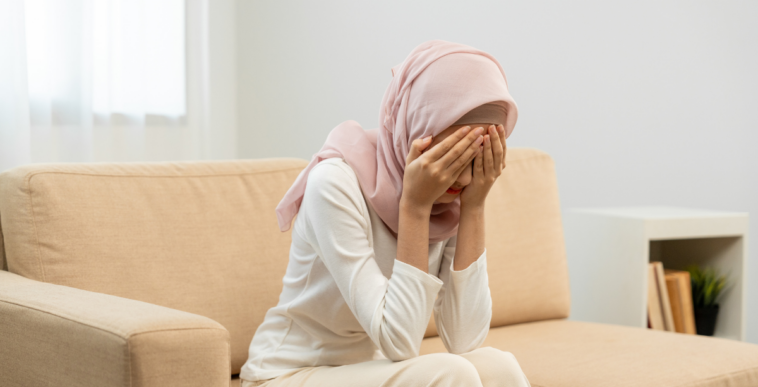Muslim woman with her face in her hands