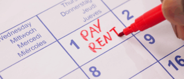 Someone writing "pay rent" in red on a calendar.