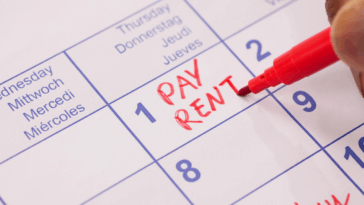 Someone writing "pay rent" in red on a calendar.