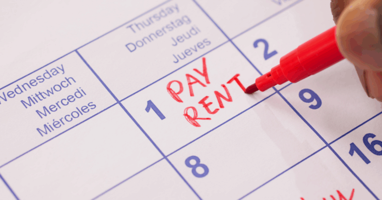 Someone writing "pay rent" in red on a calendar.