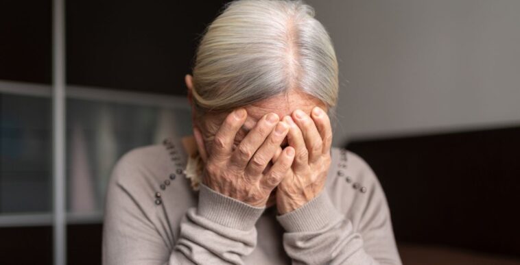 Depressed Senior Woman Covers Her Face With Both Hands.