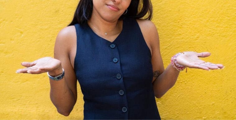 Young woman shrugging with her hands to the sides.